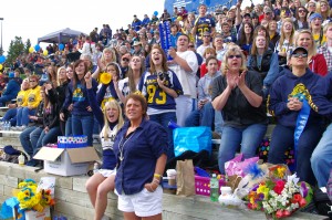 Fans wear blue and gold while screaming in support of the football team. 